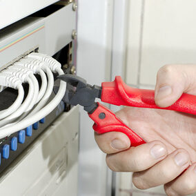 Hand with cutter cuts network cable